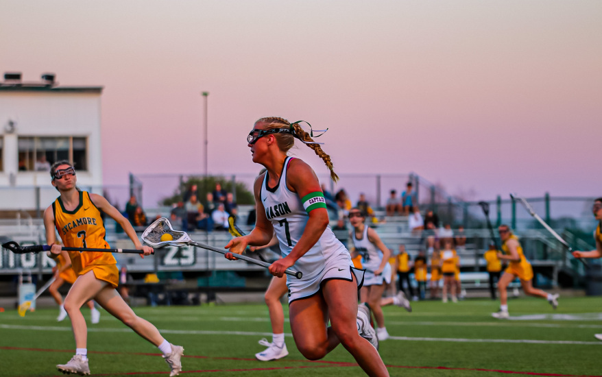 girls running down field with rackets